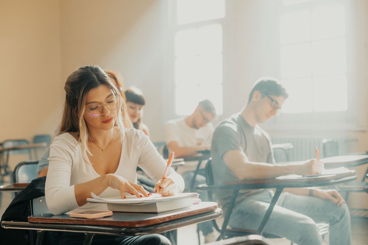 Students focused on writing, sitting in a sunlit classroom in Buenos Aires, Argentina.